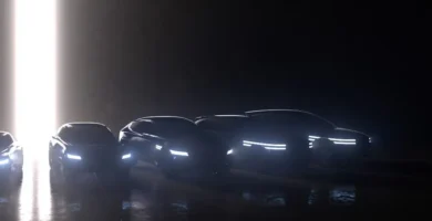 Siluetas de autos modernos con luces encendidas en penumbra.