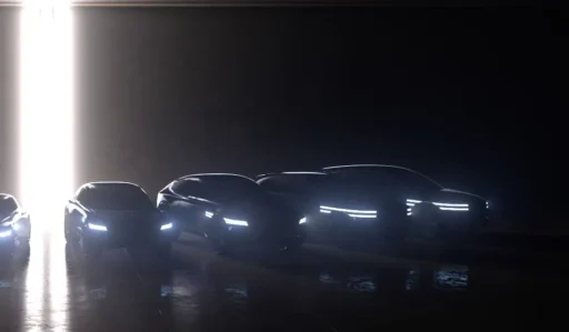 Siluetas de autos modernos con luces encendidas en penumbra.