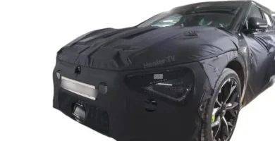 Coche deportivo negro con cubierta de camuflaje parcial.