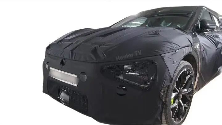 Coche deportivo negro con cubierta de camuflaje parcial.