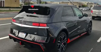 Auto negro deportivo en la calle, con diseño moderno.