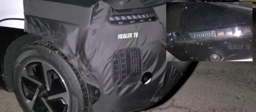 Vehículo cubierto con lona parcial, insignia "HEALER TV" visible.