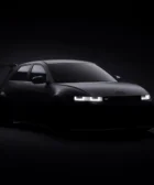 Automóvil deportivo negro en iluminación tenue y fondo oscuro.
