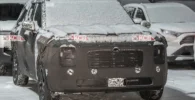 Vehículo camuflado cubierto de nieve en un aparcamiento.