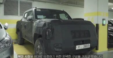 Un vehículo cubierto con camuflaje para pruebas estacionado en un garaje.