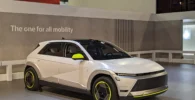 Automóvil futurista blanco exhibido en una feria de autos.