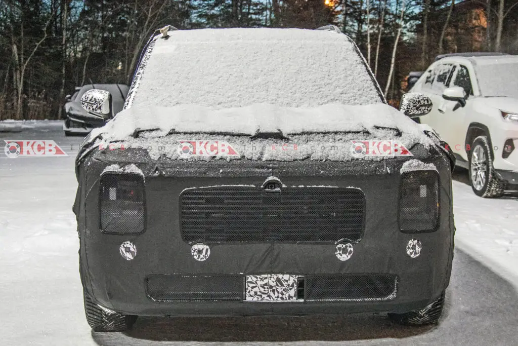 Vehículo camuflado cubierto de nieve estacionado al aire libre.