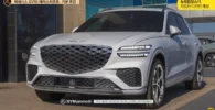 SUV Genesis GV70 blanco estacionado frente a edificio moderno.