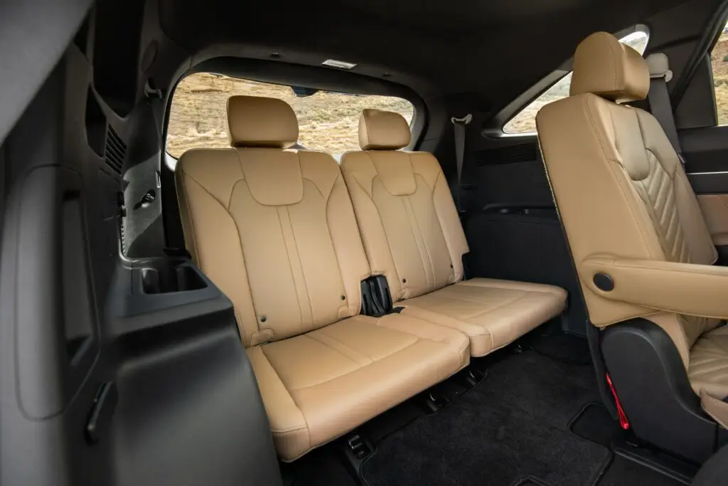 Interior de vehículo con asientos traseros de cuero color beige.