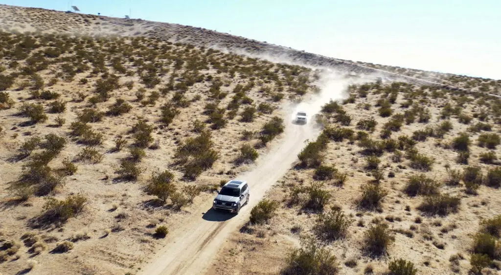 Dos vehículos circulando por un camino polvoriento en el desierto.